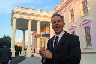 Rusty in front of the White House on June 26, 2015 holding a rainbow White House placard.