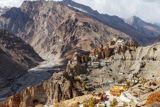 A barren looking small town sitting amongst dust brown mountains.