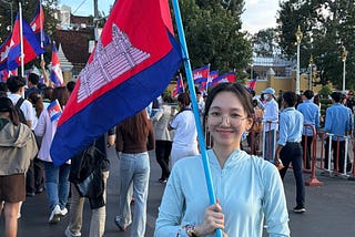 Sok Danica smiles while holding a flag.