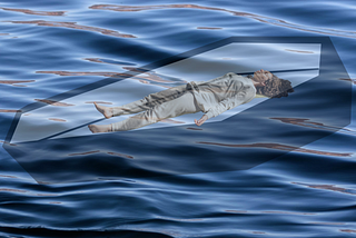 Image of a woman lying face up in an open and translucent casket in the ocean