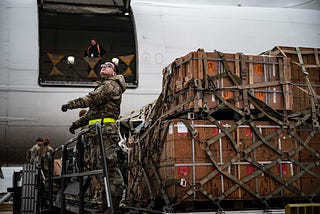 A solider getting ready to load crates of military aid for Ukraine onto a plane.