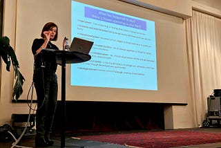 Woman at a podium speaking to her presentation