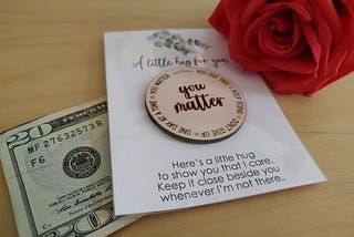 A twenty dollar bill is pictured along with a rose and a token that reads “you matter”.