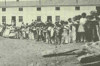 Photo of formerly enslaved people standing in front of barracks at Camp Barker in Washington DC, 1862