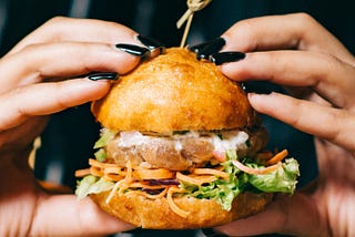 Woman gripping a stacked burger.