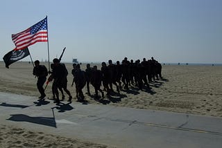 A small group of soldiers running up a beach front.