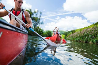 A man and a woman are canoeing on the river.