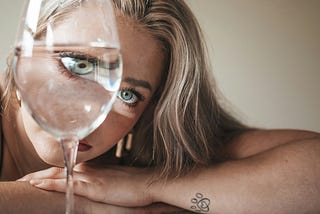 Photo of woman with eyes enlarged by wine glass.