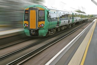 Trem verde andando sobre os trilhos em alta velocidade com o fundo desfocado devido a velocidade.