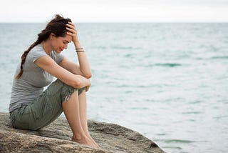 A woman sitting on a rock in despair