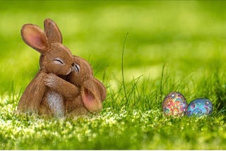 Two cute bunnies hugging and two foil wrapped Easter eggs