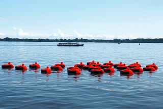 25 figures cling to inner tubes on the water, each figure representing more than one million refugees across the globe.