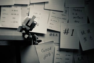 image of a robot sitting close to a lot of comments written on papers stuck to the wall