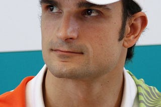 Luizzi wearing the Force India team shirt and cap against a blue and white background.