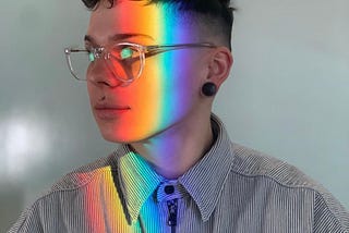 Side profile image of Nikki with prismatic rainbow light down their face