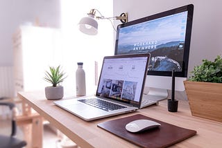 Laptop and monitor sitting on a light wooden desk