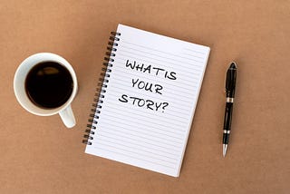 What is your story? text on note pad on top of wood desk.