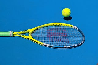 A tennis racquet next to a tennis ball