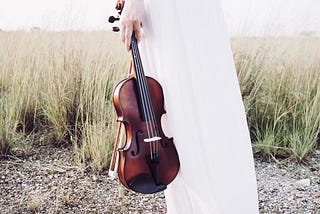 Person’s hand holding a brown violin