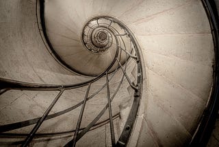 Black and white photo of the spiral railing of the staircase inside the Arc de Triomphe in Paris