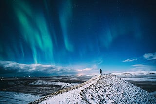 A man standing with the Aurora in the sky.
