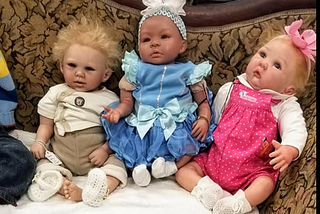 Three lifelike baby dolls whose dark eyes indicate stress