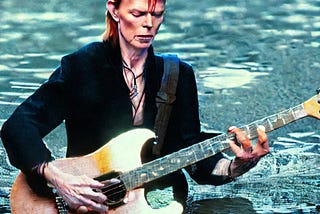 Image of David Bowie with a Ziggy Stardust-style haircut, up to his waist in flood waters, playing an old looking electric guitar (generated by Stable Diffusion).