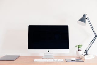 computer on desk with lamp and plant next to it