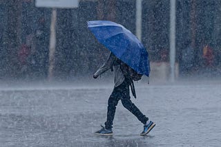 Man with blue umbrella walking in the rain.