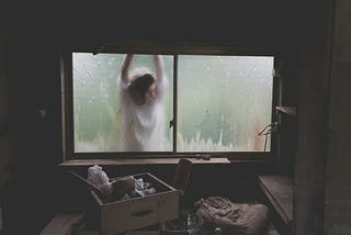 Looking out through the filthy window of a garden shed, a woman can be seen, her face pressed against the glass. She is wearing a white dress and veil. Her arms are raised in a way which suggests her wrists — unseen — may be tied to each other and to the shed.