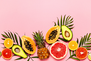 Tropical fruit against pink background. Citrus, avocado, papaya and pineapple.