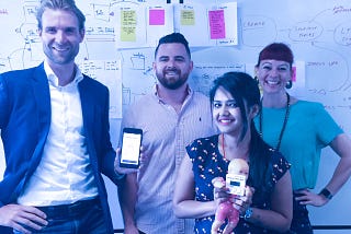 Four people holding a phone with an app prototype.