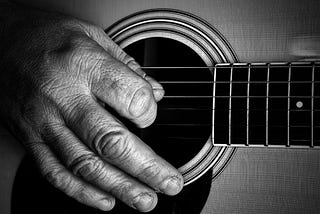 An old man’s hands playing a guitar.
