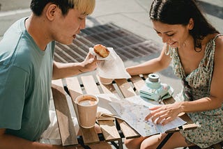 diverse-couple-having-breakfast-in-cafe-while-exploring-map
