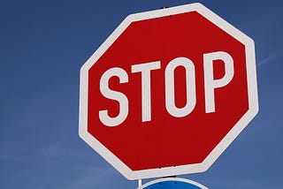Image shows a huge stop sign filling the right of the image with a blue sky background.