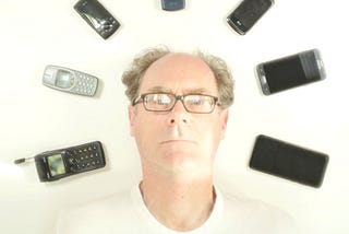 Self portrait of my head surrounded by all the cell phones that I’ve owned
