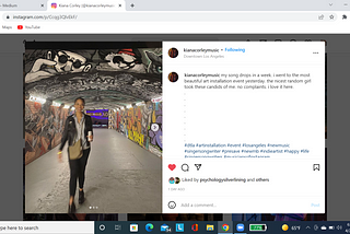 A slightly blurry picture of a young, lightskinned black woman standing in a bright, graffitied tunnel, smiling and holding a cup. She is wearing black leggings, black ankle boots, a blue button-up shirt, and a black leather jacket. She is carrying an olive-colored cross-body bag.