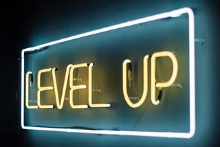 A neon sign saying ‘level up’ is shown. Level up is written in yellow neon lights