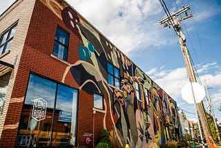 A colorful, abstract mural on the outside of a brick building.