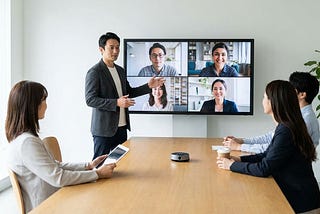 Manager leading a virtual team meeting while remote and in-office employees share stories on a video call