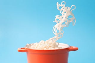 noodles in a red pot against a blue background