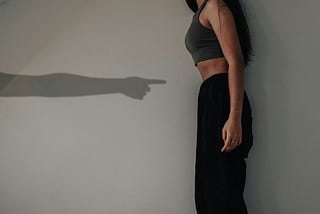 A long arm with a finger pointing at a woman’s waist who is standing.