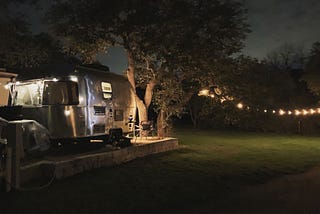 My neighbor’s silver airstream parked next to me under a string of bulb lights