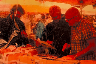 Three men at a market stall selling records.