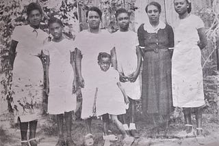 From right to left, Altagracia Joseph dressed in dark clothing, standing with Lydia Joseph Allen in the center and her granddaughters, born in Tela, Honduras.