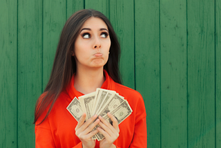 Woman pouting and holding up cash — for my article on How I Use Google Traffic To Make Money With Medium