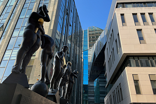 Five bronze statues in the street in Leipzig, each holding a or wearing a gilded sigil.