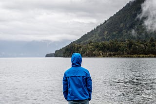 person in jacket looking at lake