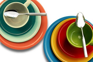 Two stacks of colorful dishes, viewed from above. Each has plates of successively smaller size, with a mug and a spoon on top.