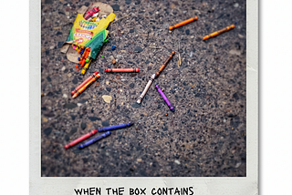 Crayons scattered on the pavement next to their crushed box